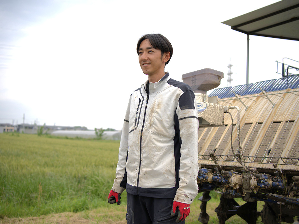 田植え機の前でインタビューに答える様子